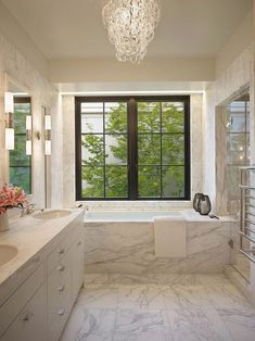 a large bathroom with marble counter tops and white walls, along with a chandelier hanging from the ceiling