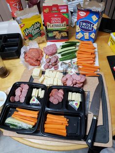 an assortment of meats and cheeses on trays next to other food items