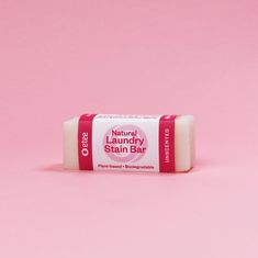 a bar of soap sitting on top of a pink surface with the words natural laundry stain bar