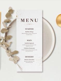 a white plate topped with a menu next to gold utensils