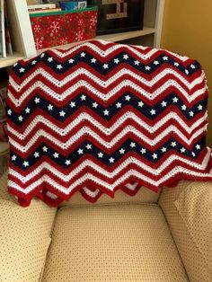 a red, white and blue crocheted blanket sitting on top of a couch