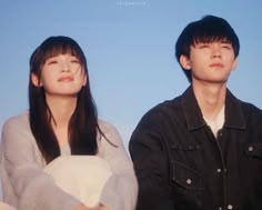 a man and woman sitting next to each other on a bench in front of a blue sky