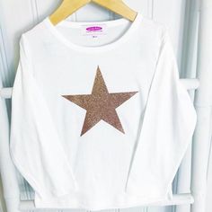 The newest addition to our Candy Bows Tshirt Collection. A Whitek cotton long or short sleeve tshirt is embellished with a vinyl large Rose Gold Super Star that shimmers in the light. Perfect for little girls to wear all year round, to any party, or just to look sassy at the weekend.  The Star is available in a variety of vinyls:Rose Gold GlitterRose Gold ShinyLeopard PrintSnakeskin PrintRainbow Oil The t-shirt is a non-personalised tshirt (personalised design available in hoodie on our website) Long Sleeve Cotton Tops With Glitter Print, White Glitter Print Crew Neck Top, Trendy Long Sleeve Glitter Top, Dance Hoodies, Tshirt Collection, Glitter Rose Gold, Birthday Girl Outfit, Girls T Shirt, Personalized Hoodies