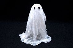 a white plastic ghost with black eyes on a black background