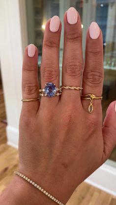 a woman's hand with three different rings on her fingers and one ring in the middle