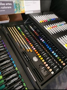 an assortment of art supplies on display in a box with other items around the table