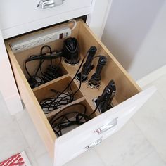 an open drawer with many cords and other items in it on the floor next to a rug