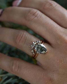 a woman's hand with a diamond ring on top of her finger and the other hand holding an engagement ring