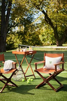 two chairs and a table with tennis balls on the grass