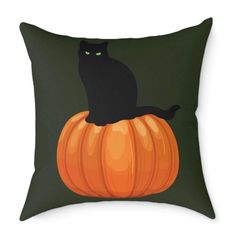 a black cat sitting on top of a pumpkin pillow with green eyes in the dark