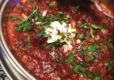 a large metal bowl filled with food and garnished with parsley on top