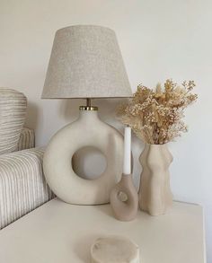 a table with two vases and a lamp sitting on top of it next to a couch