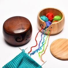 a wooden box filled with yarn next to a pair of scissors and a knitting needle