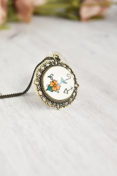 a white necklace with an orange flower on it and a black cord attached to it