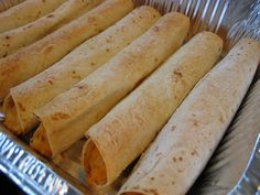 several burritos in a metal pan lined up