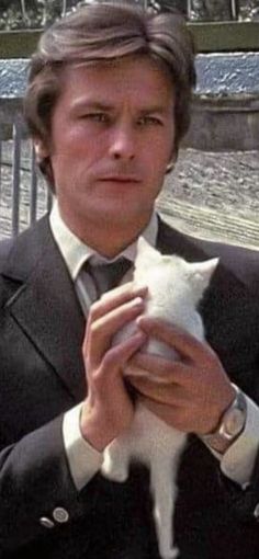 a man in a suit holding a white cat