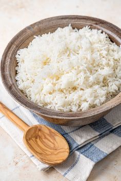 white rice in a bowl on a blue and white checkered napkin with wooden spoon