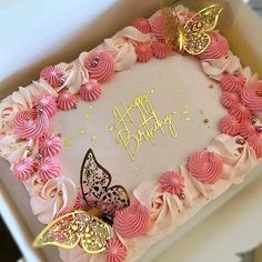 a birthday cake with pink frosting and gold butterflies on it, in a box