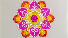 an embroidered design on a white surface with orange and pink accents, in the shape of a flower