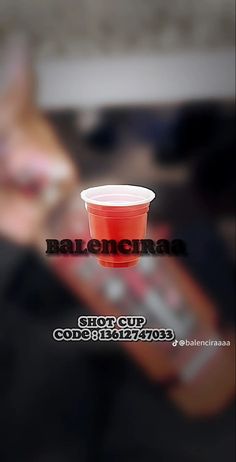 a red cup sitting on top of a table next to a woman's face