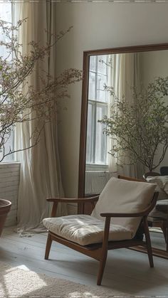 a chair sitting in front of a large mirror next to a potted plant on a table