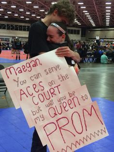 two people hugging each other while holding signs