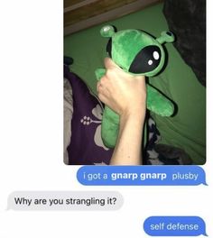 a person holding a green stuffed animal in their left hand and texting on the right