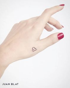 a woman's hand with a small tattoo on the left side of her ring finger