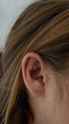 a close up of a person's ear with a gold nose piercing