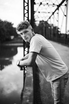 a young man leaning on a rail near water