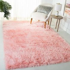 a living room with a pink rug on the floor next to a chair and table