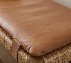 a brown leather seat cushion on a wicker bench