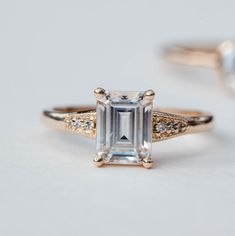 two engagement rings with an emerald cut diamond