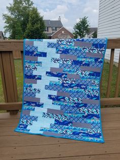 a blue and gray quilt sitting on top of a wooden deck