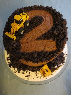 there is a cake with the number two on it and construction trucks in the middle