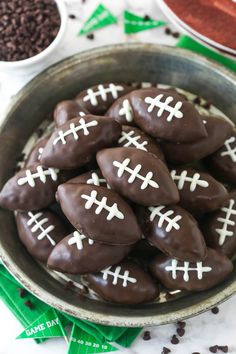 chocolate football cookies in a bowl with white crosses on them and cocoa chips scattered around