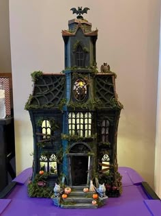 an elaborately decorated doll house sits on a purple table