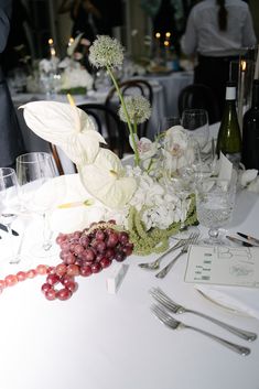 the table is set with wine glasses, silverware and flowers