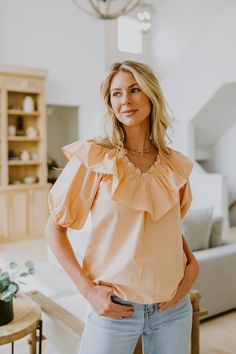 If you're looking for the perfect "date night" outfit, look no further! This gorgeous women's peach blouse is a beautiful blouse to pair with jeans or a skirt! Our Peach Ruffle Blouse is a v-neck blouse made with 100% Cotton. Elasticized on the neckline. It has short puff sleeves with elastic cuffs. Finished clean hem. Fits true to size. Available in women's sizes: Small Medium Large Peach V-neck Summer Blouse, Summer Peach V-neck Blouse, Peach Feminine Blouse For Day Out, Chic Orange Ruffled Blouse, Feminine Peach Blouse For Day Out, Chic Orange Blouse With Ruffles, Feminine Peach V-neck Blouse, Summer V-neck Peach Blouse, Elegant Apricot Summer Blouse