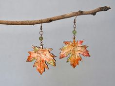 two leaf shaped earrings hanging from a tree branch