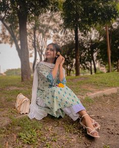 a woman sitting on the ground talking on her cell phone