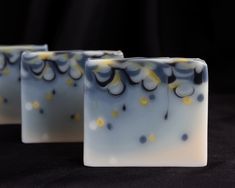 three soap bars sitting on top of each other in front of a black background with yellow and white swirls