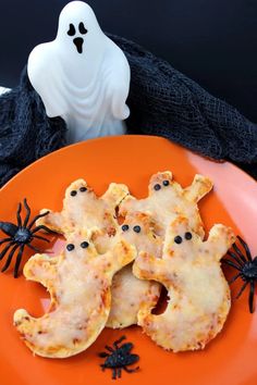 an orange plate topped with cheese covered cookies and ghost shaped candies on top of it