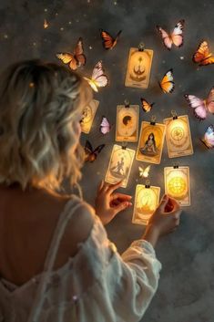 a woman is surrounded by butterflies and playing cards with candles in the shape of zodiac signs