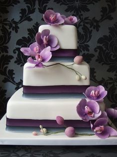 a three tiered cake with purple flowers on top