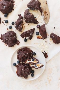 chocolate desserts with blueberries and whipped cream on a white plate next to a wooden spoon