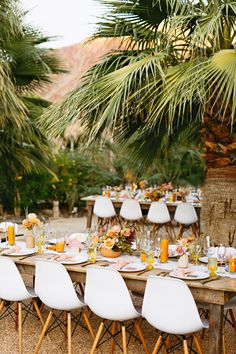 a table set up with white chairs and plates