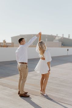 a man and woman standing on top of a roof with their arms in the air