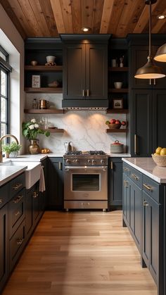 a kitchen with wood floors and black cabinets, white counter tops and wooden ceilinging