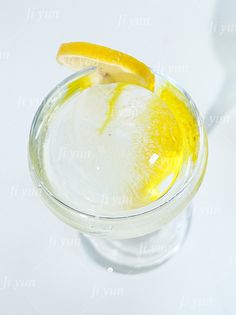 a glass filled with ice and lemon wedges on top of a white countertop